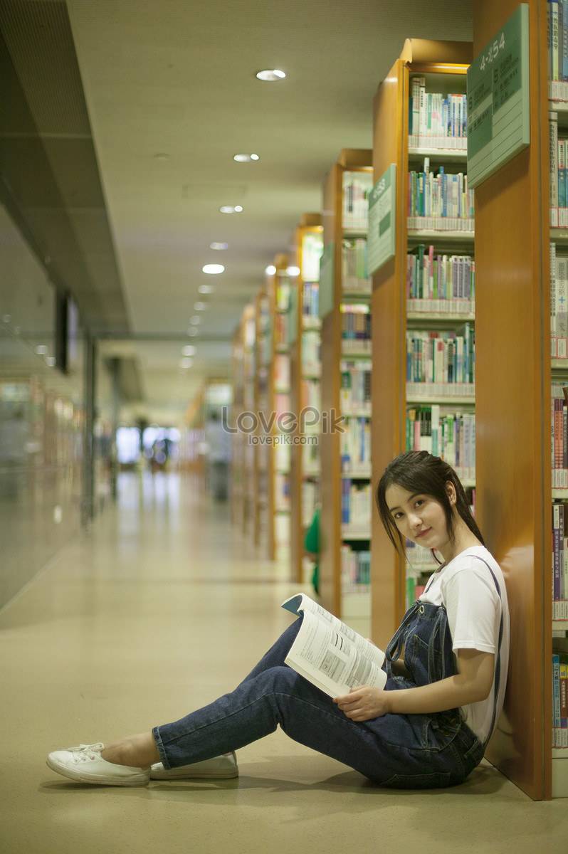 รูปนักเรียนหญิงในห้องสมุดโรงเรียนกำลังอ่านหนังสืออย่างหนัก Hd ภาพถ่าย