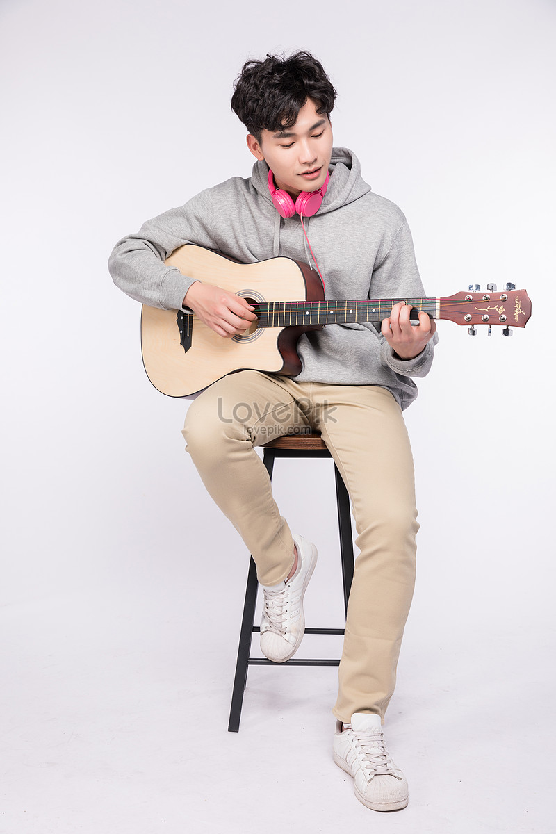 Portrait Of Seated Young Man With Guitar In Hand Resting While Posing In  Studio Background Stock Photo, Picture and Royalty Free Image. Image  51844133.