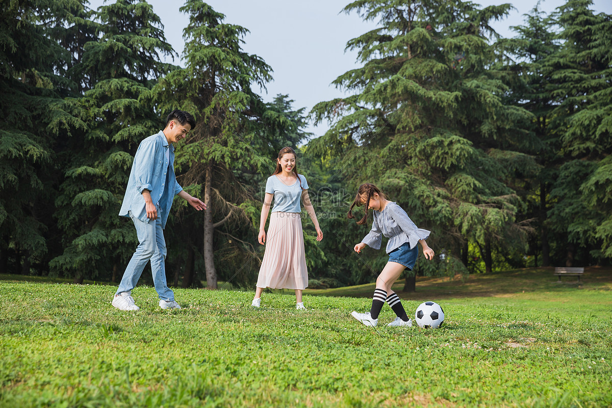 Семья играет в футбол. Фото семья футбол лужайка. The owner and Corgi are playing on the grass.