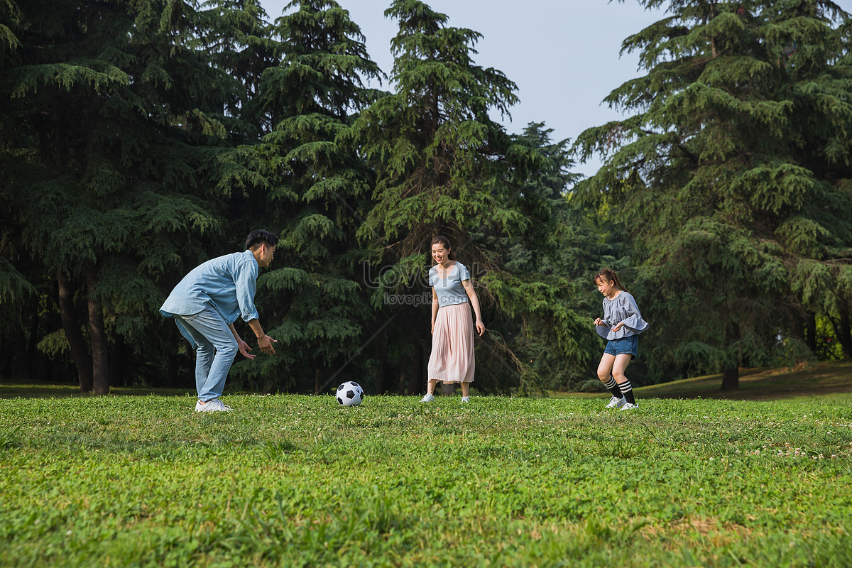 Семья играет в футбол. The owner and Corgi are playing on the grass.