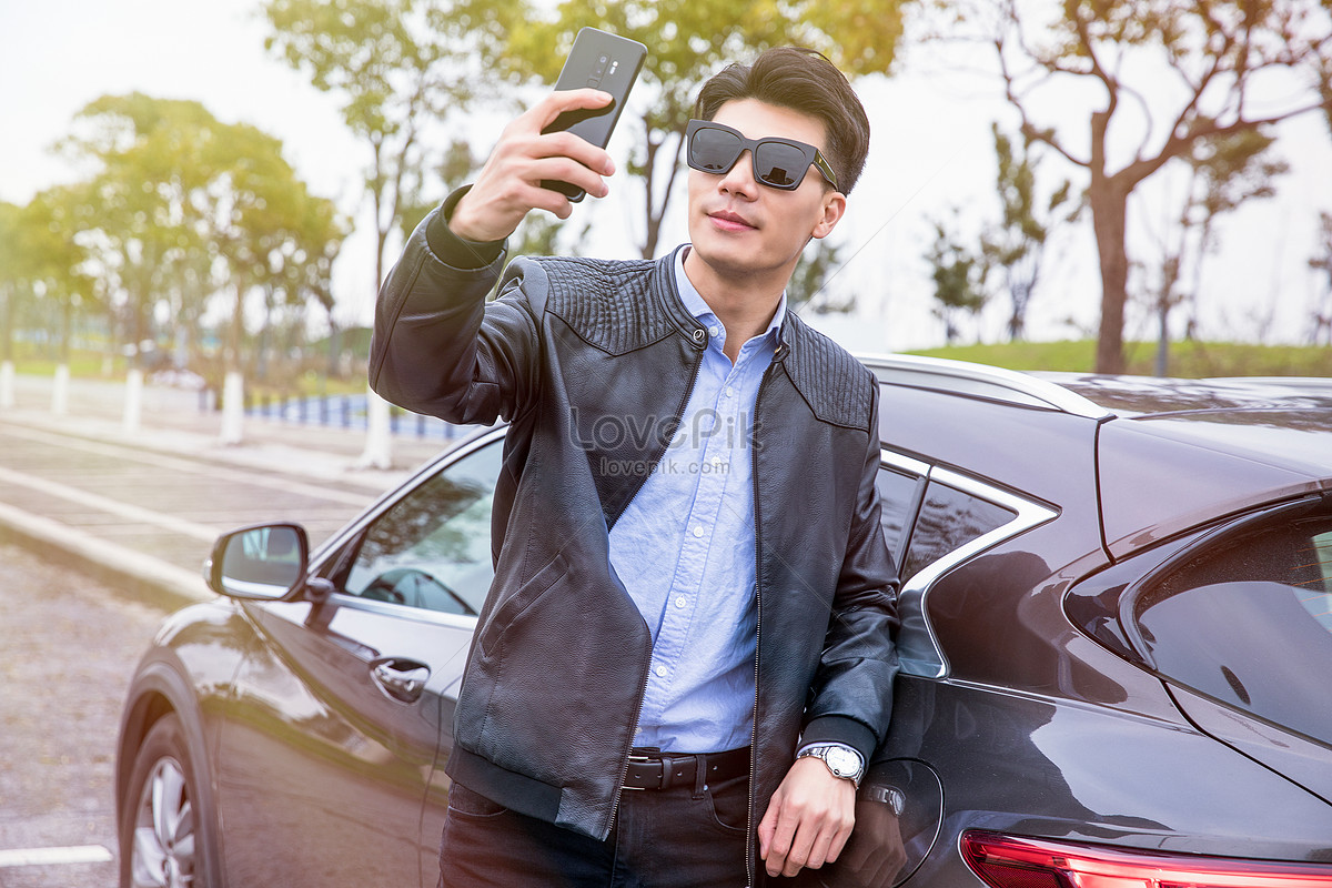 Man in black, blue, and red floral button-up collared shirt and gray pants  sitting on car hood during daytime photo – Free Wooden Image on Unsplash