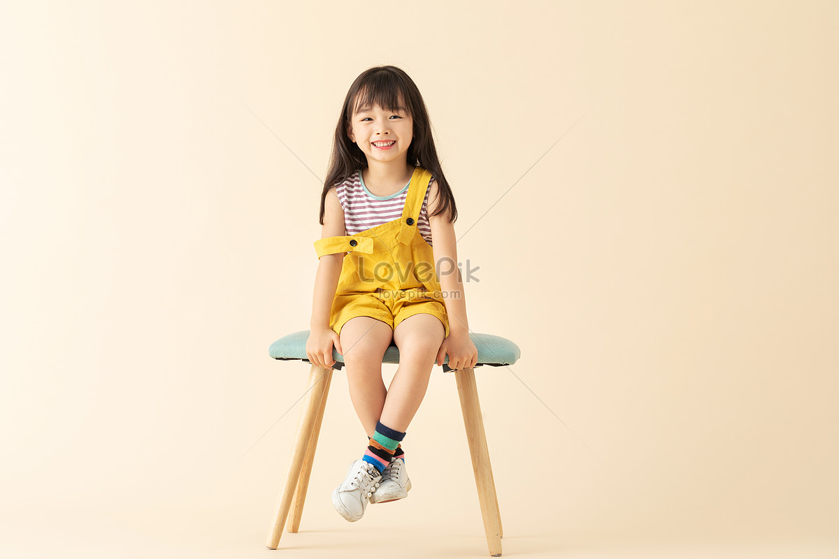 Маленькая девочка сидит на стуле фото