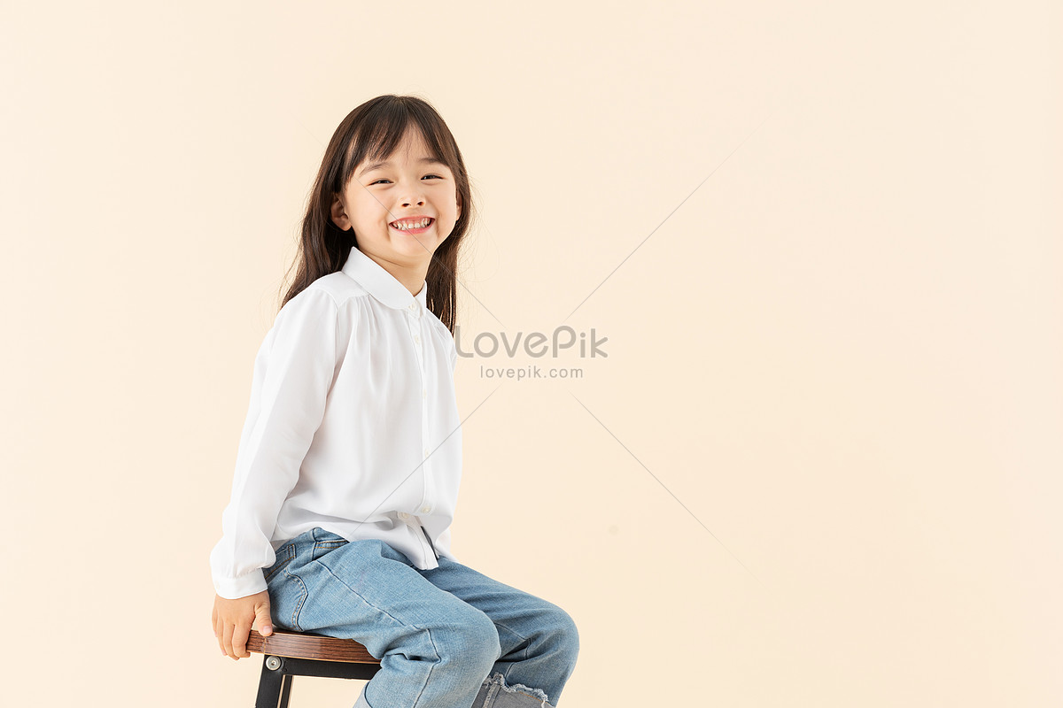 Маленькая девочка сидит на стуле фото