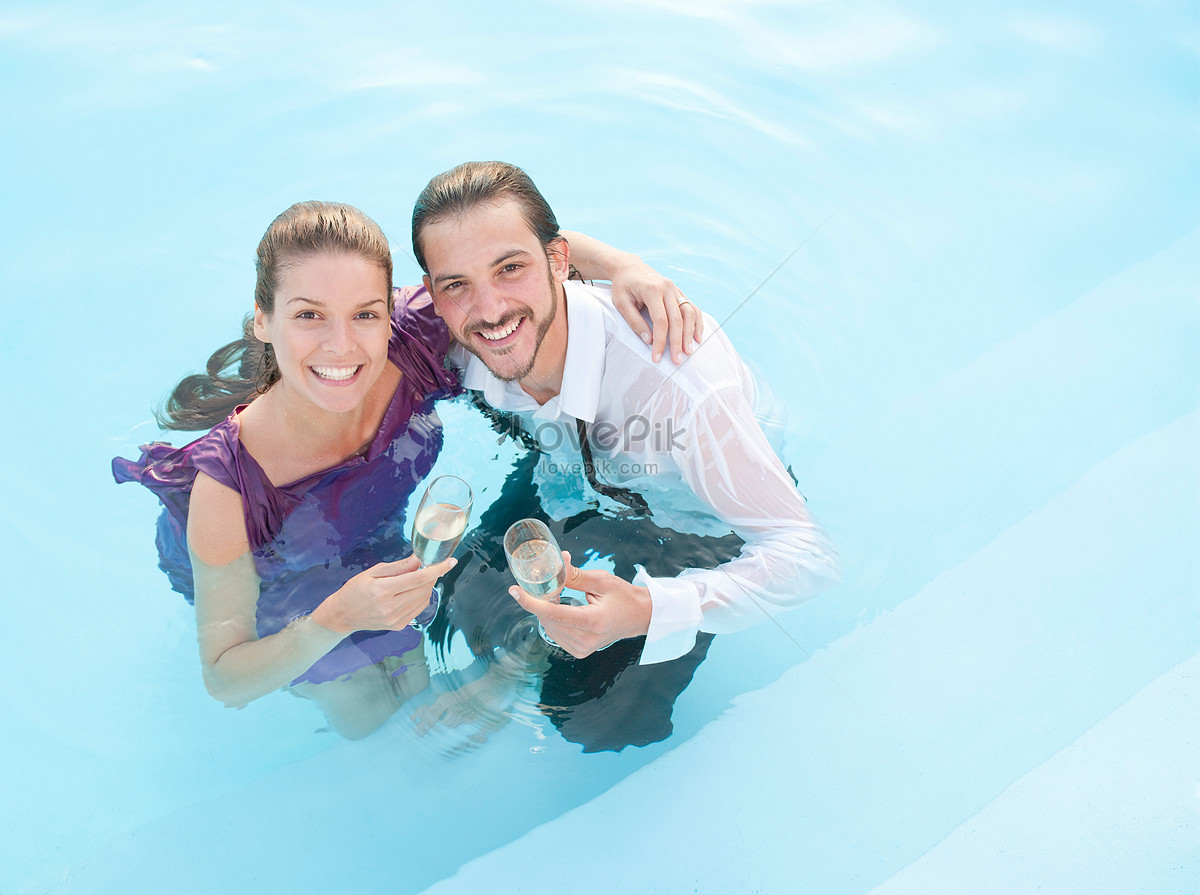 Very happy couple wearing sunglasses enjoy each other in swimming pool. Man  holding woman on hands Stock Photo - Alamy