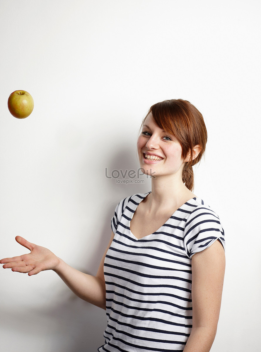 Кидает яблоко. Девушка бросает яблоко. Бросок яблока. Рука подбрасывает яблоко. Белая студия бросает яблоко вверх.