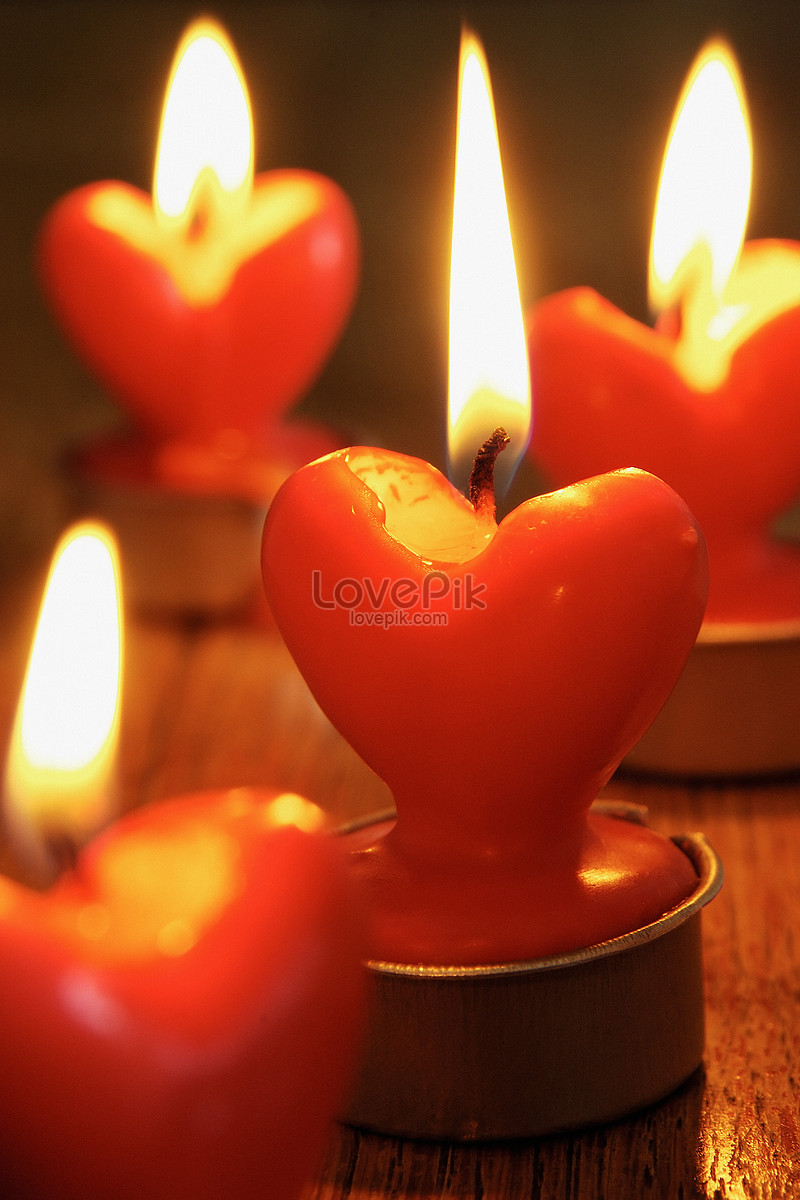 Two burning heart shaped candles over purple background, Stock image