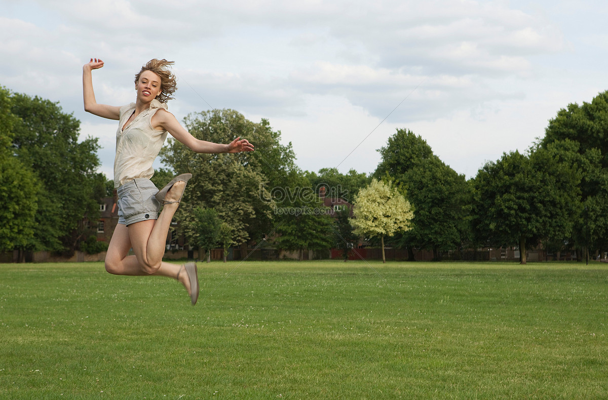 Женщина прыгает в классики. Женщина в прыжке ноги вытянуты. Девушка бежит прыгает по траве.