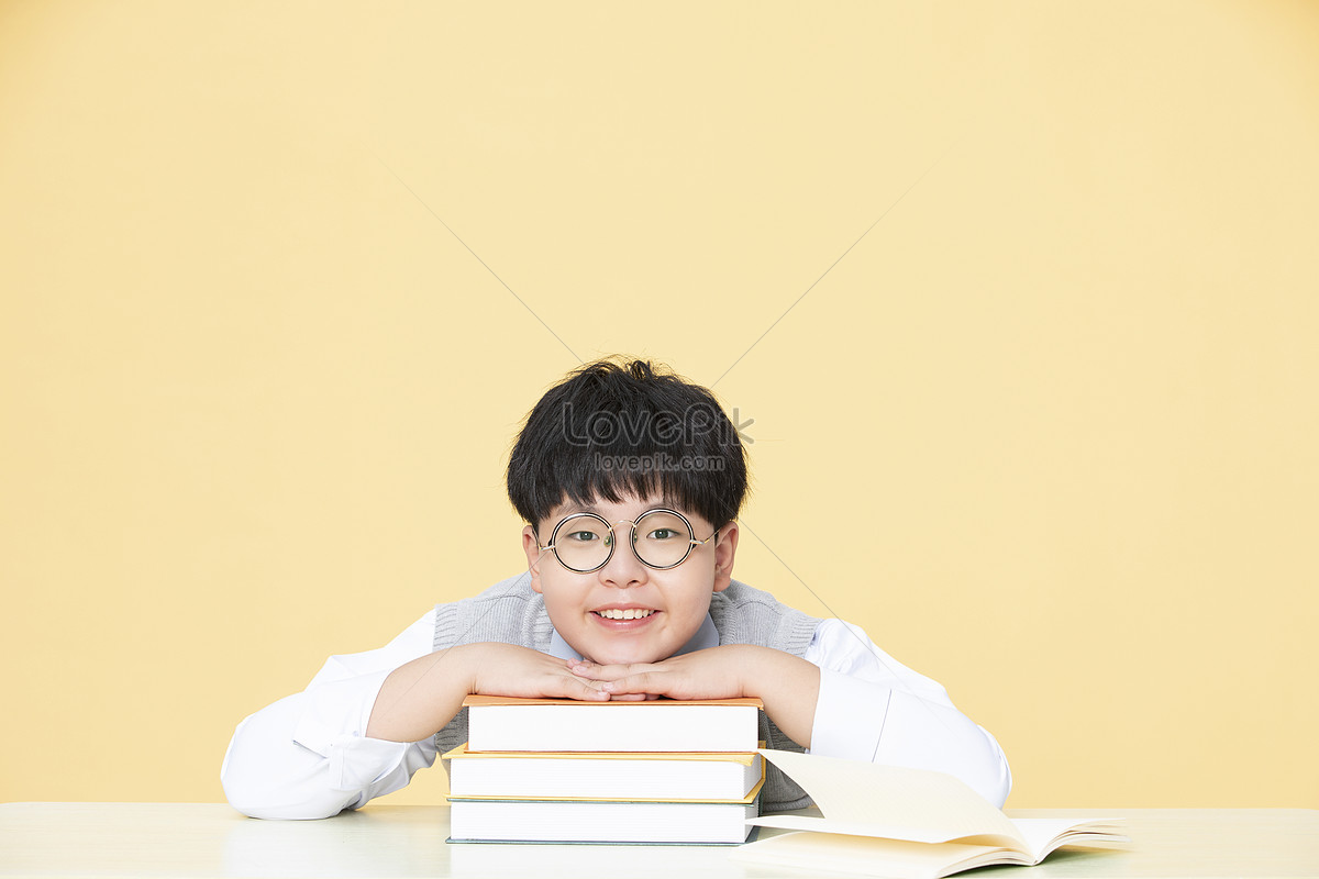 A little boy who likes to do homework lying on a book who likes to read, happy boy, and homework, book HD Photo