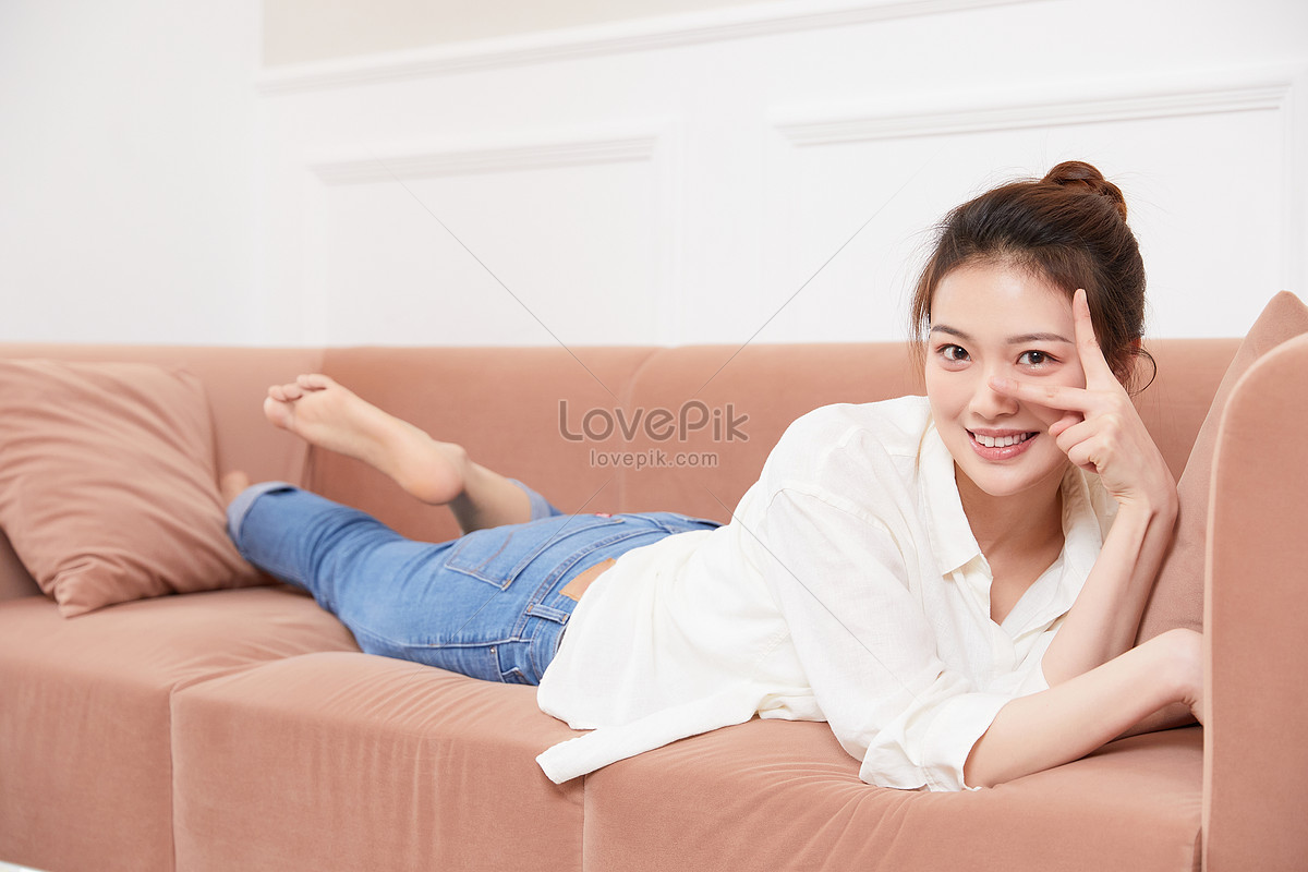 Menina sorridente, deitada no sofá confortável, desfrutando de