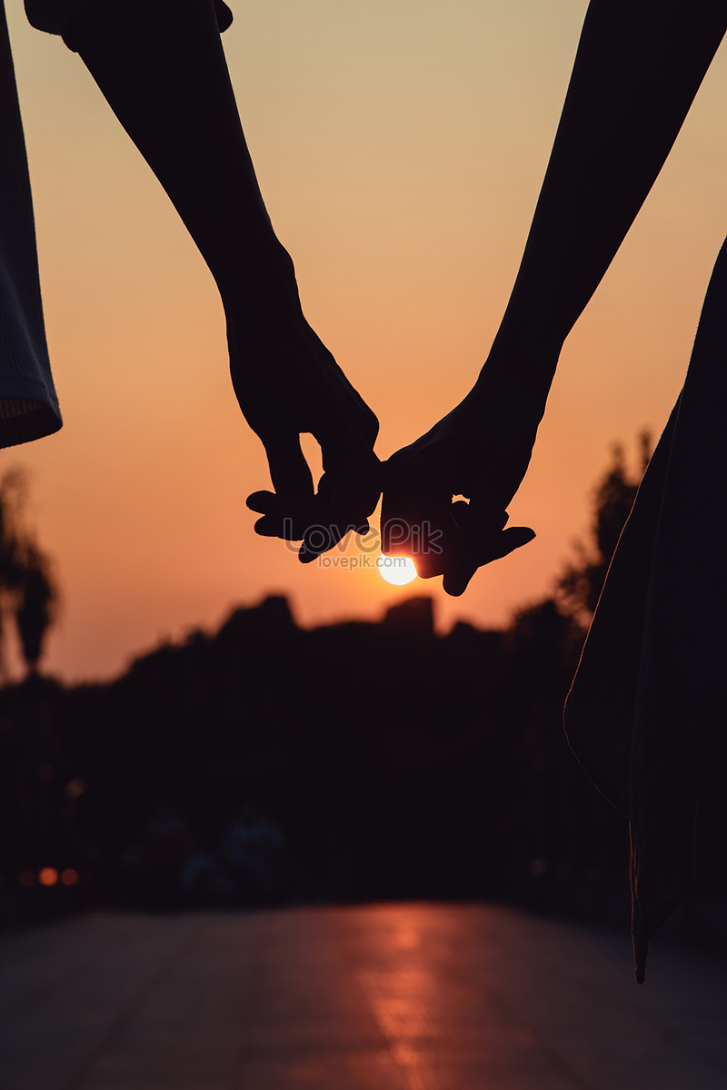 couple holding hands silhouette sunset