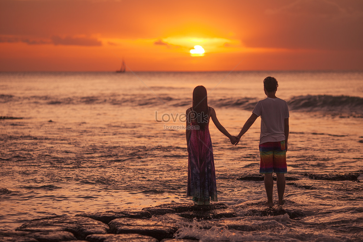Romantic lovers in the journey look at the sunset in the sea stock pictures.  & images