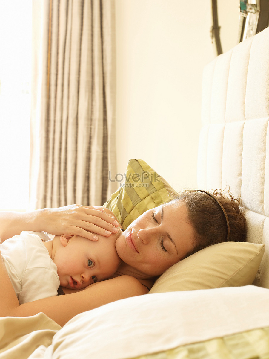 Женщина держит ребенка на кровати.