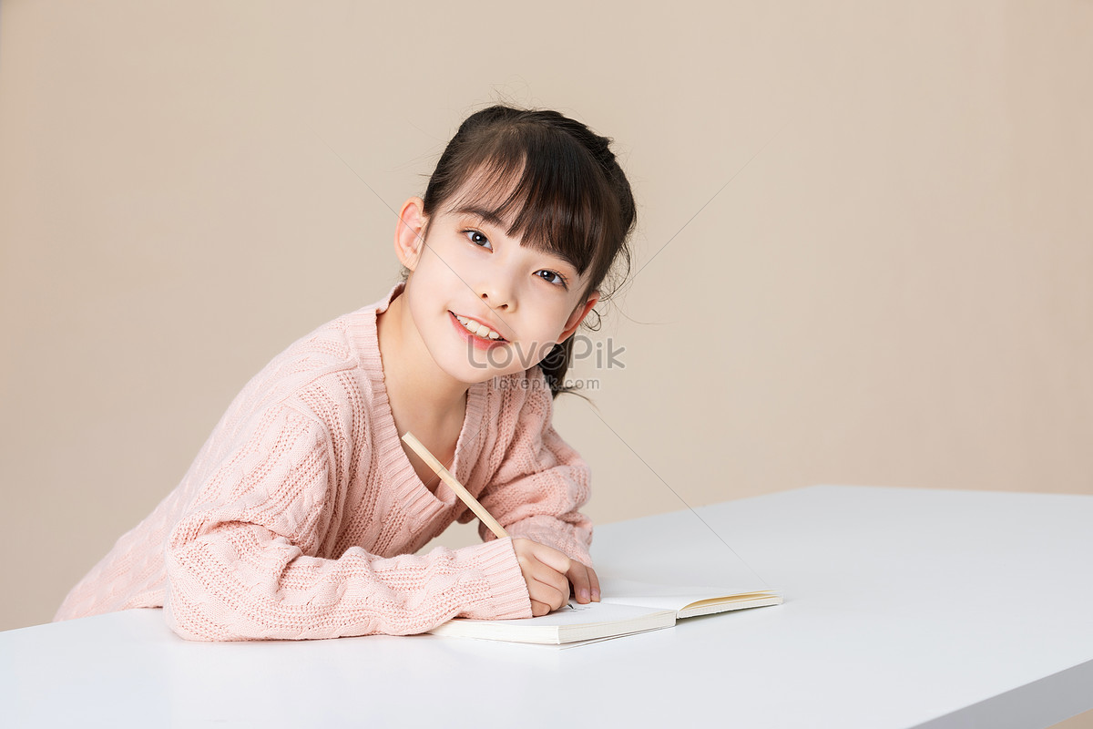 Little girl lying on the table writing and doing homework Photo