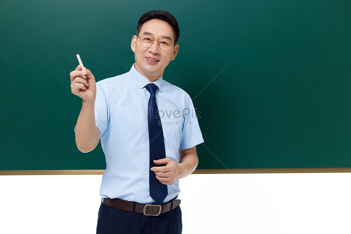 The Middle Aged Male Teacher Holds The Chalk In Front Of The Blackboard ...