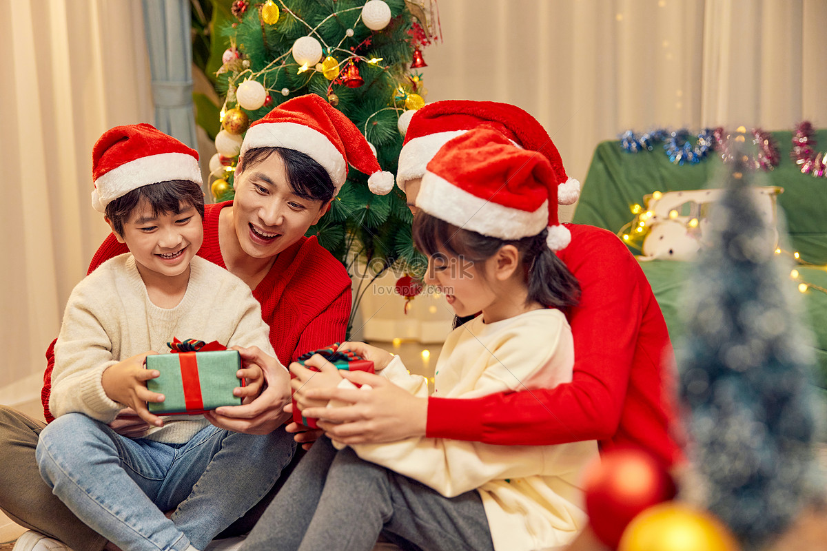 A Family Of Four Happily Unwrap Presents At Christmas Picture And HD ...