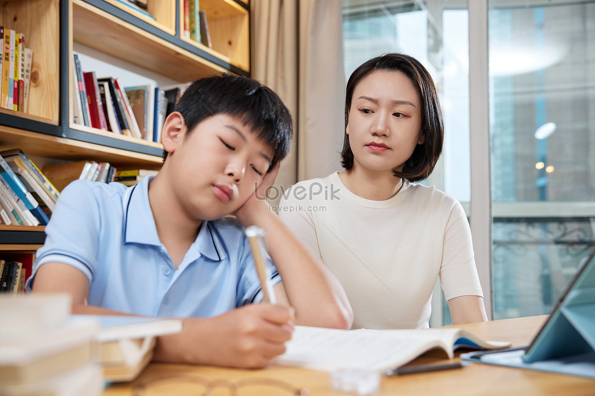 Mother watching her son doing homework Photo
