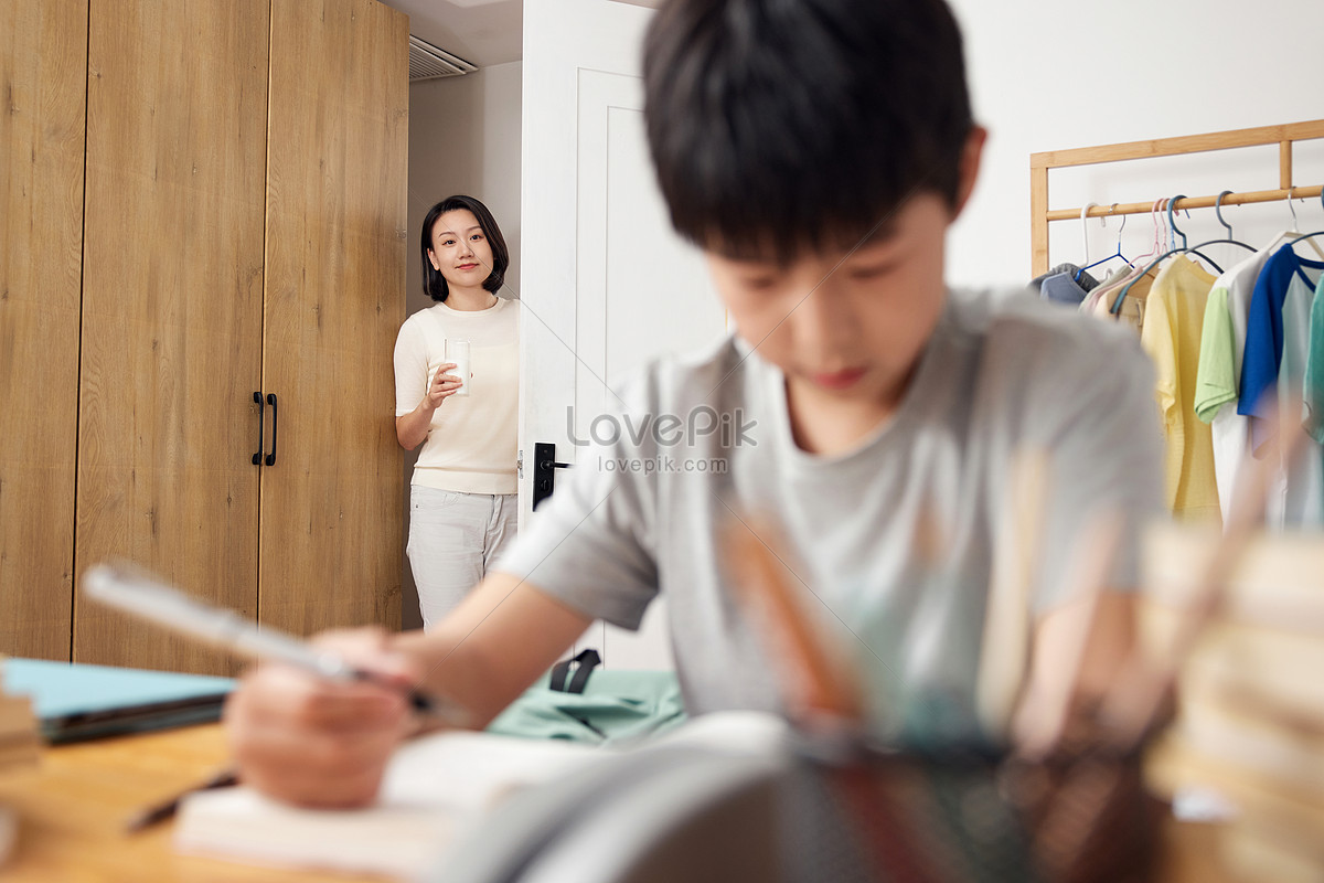 Mother delivers milk to child doing homework Photo