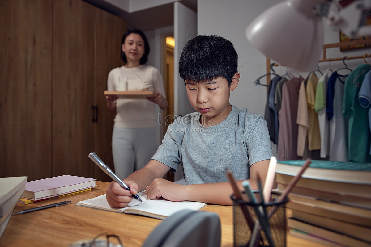 Mother takes care of her son who is doing homework late at night Photo