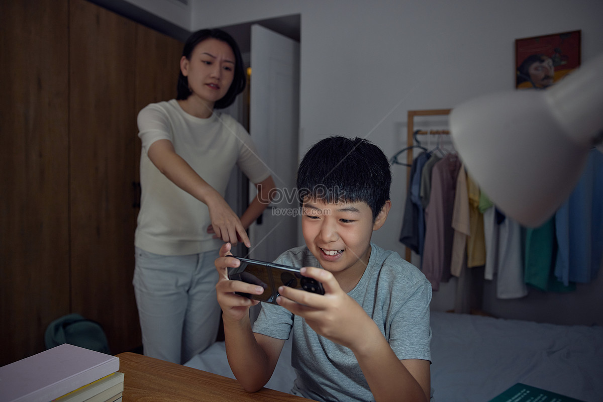 Boy who plays mobile phone without doing homework is scolded by mother Photo